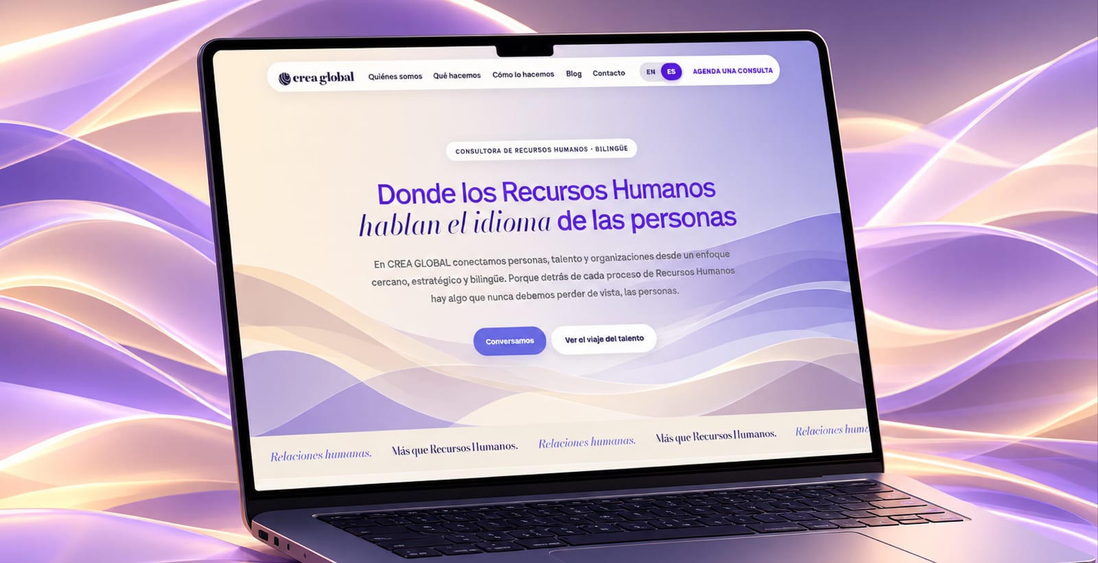 Sitio de Crea Global en un portátil sobre ondas violetas